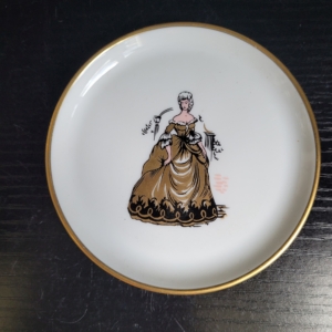 Kleiner Teller, weiß, mit Goldrand. Motiv: Frau mit langem goldenen Kleid