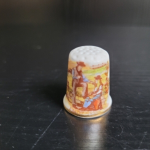 Fingerhut, weiß, mit Goldrand. Motiv: Pärchen an einer Mauer, Rückseite: Schriftzug