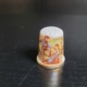Fingerhut, weiß, mit Goldrand. Motiv: Pärchen an einer Mauer, Rückseite: Schriftzug