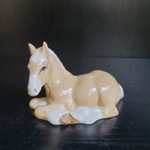Liegendes Pferd in hellbeige und weiß