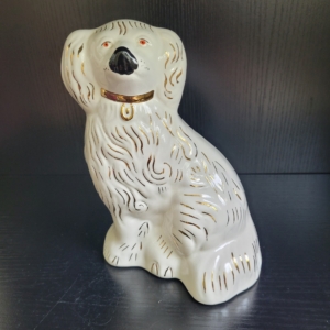 Hund, sitzend, weiß, mit goldenem Halsband und Applikationen, schwarzer Nase und roten Augen
