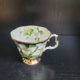 Kaffeetasse, weiß, außen schwarz, mit Goldrändern und weißen Blüten