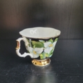 Kaffeetasse, weiß, außen schwarz, mit Goldrändern und weißen Blüten