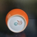 Vase, Kugelförmig, weiß, außen orange, mit handbemaltem Blumendekor in schwarz weiß. Unterseite mit Stempel