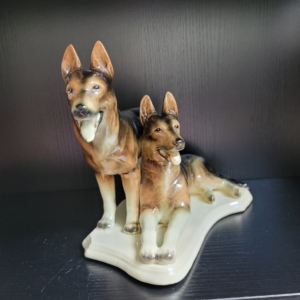 2 Schäferhunde, einer liegend, einer stehend, in Naturtönen beige, braun, schwarz