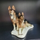 2 Schäferhunde, einer liegend, einer stehend, in Naturtönen beige, braun, schwarz